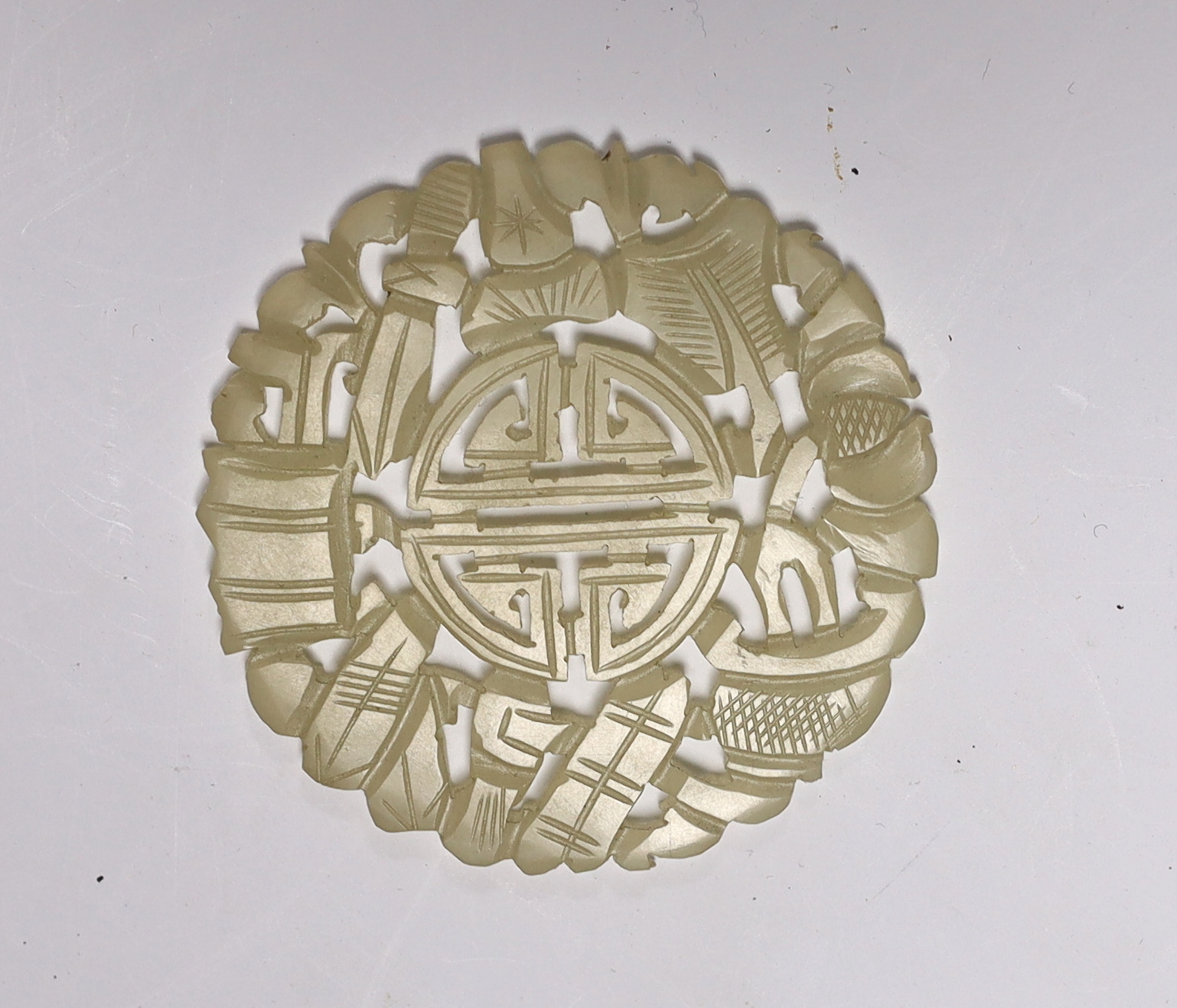A Chinese carved pale celadon disc, 5.5cm in diameter